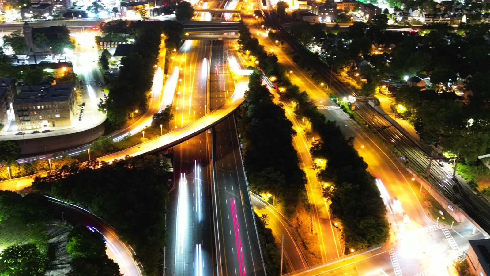 Lit parking lot, cars, and neighborhood streets after dark